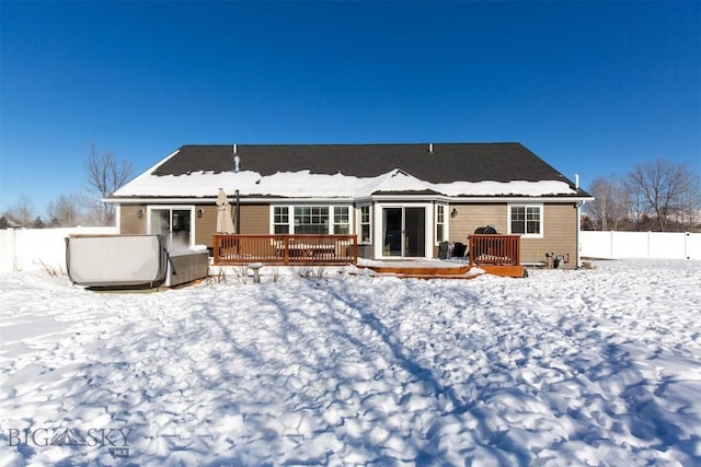 snow covered rear of property featuring a wooden deck and a jacuzzi