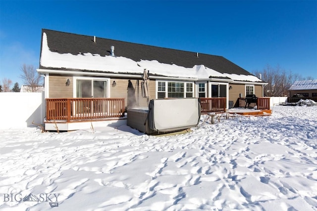 snow covered property with a wooden deck and a hot tub