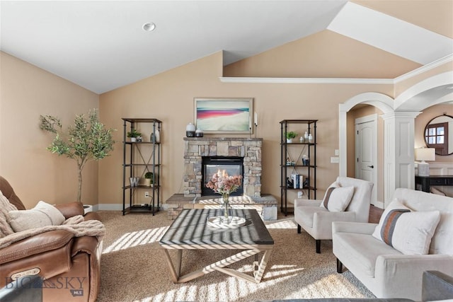 carpeted living room featuring decorative columns, vaulted ceiling, and a fireplace