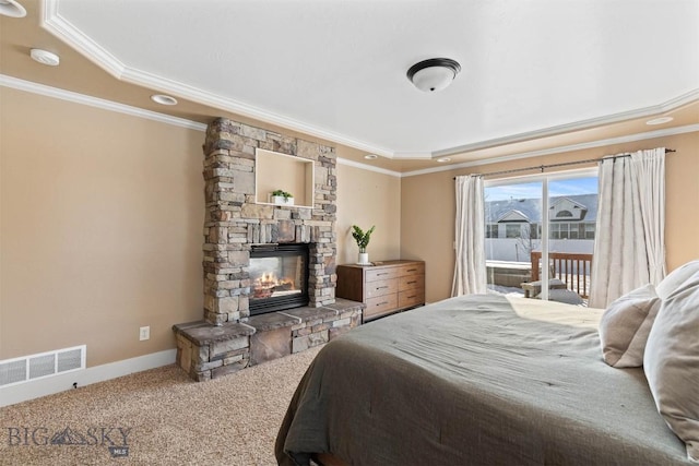 carpeted bedroom with a tray ceiling, ornamental molding, and a stone fireplace