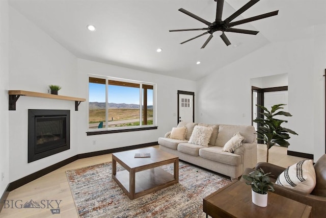 living room with ceiling fan, a mountain view, light wood-type flooring, and lofted ceiling