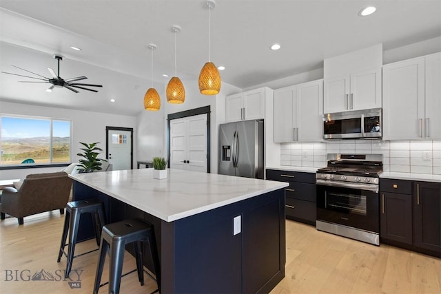 kitchen with pendant lighting, appliances with stainless steel finishes, backsplash, white cabinets, and a center island