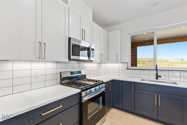 kitchen featuring light stone countertops, decorative backsplash, sink, white cabinets, and stainless steel appliances