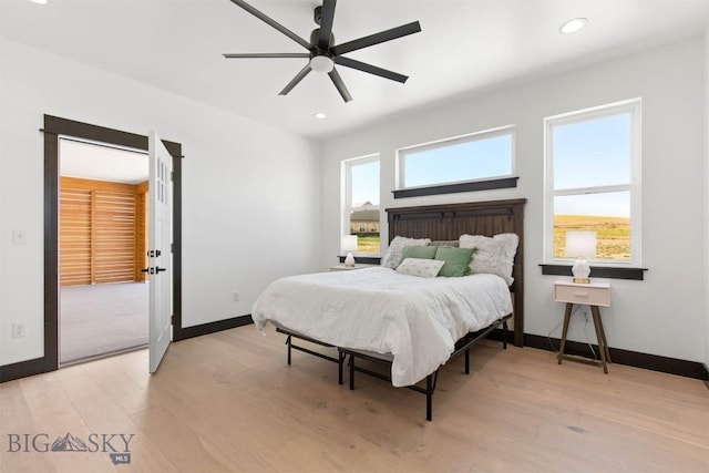 bedroom featuring light wood-type flooring, ceiling fan, and multiple windows