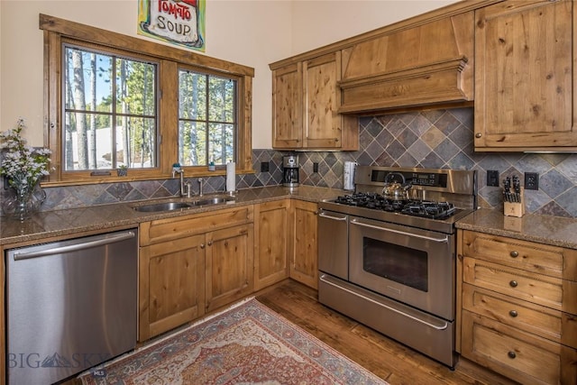 kitchen featuring stainless steel appliances, tasteful backsplash, dark stone countertops, sink, and dark hardwood / wood-style floors