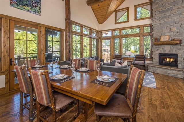 dining area featuring high vaulted ceiling, dark wood-type flooring, and a stone fireplace