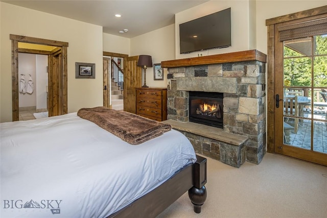 carpeted bedroom featuring a stone fireplace and access to outside