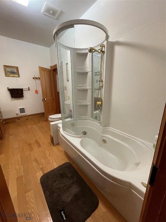 bathroom with hardwood / wood-style flooring, toilet, and shower / bathing tub combination