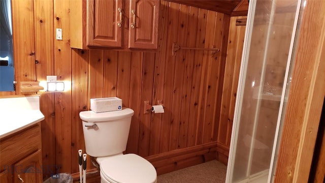 bathroom featuring vanity, toilet, and wooden walls