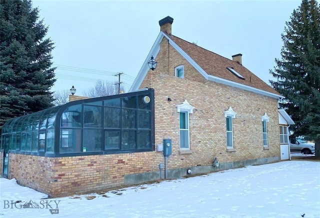 view of snowy exterior featuring a sunroom