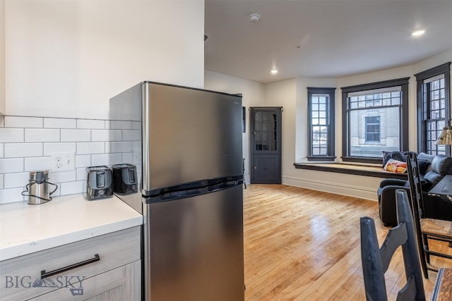 kitchen with backsplash, stainless steel fridge, and light wood-type flooring