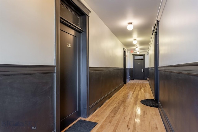 hall with wood-type flooring and wood walls