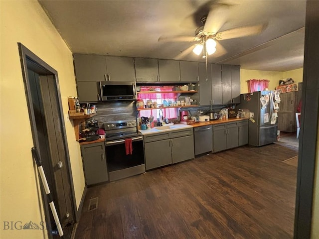 kitchen with gray cabinets, dark hardwood / wood-style floors, sink, ceiling fan, and stainless steel appliances