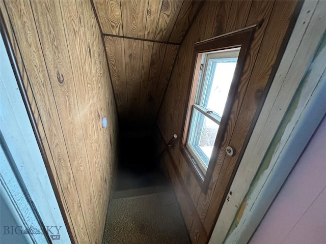 stairway with vaulted ceiling, plenty of natural light, wooden ceiling, and wood walls