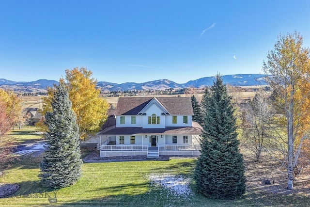 farmhouse featuring a mountain view, covered porch, and a front yard