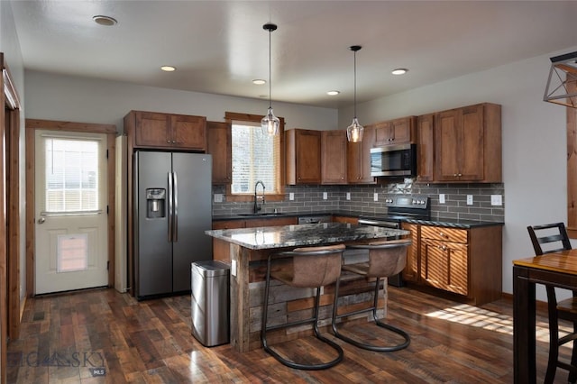 kitchen with pendant lighting, sink, dark hardwood / wood-style flooring, a center island, and stainless steel appliances