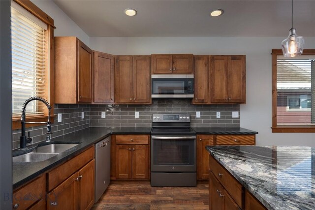 kitchen featuring stainless steel appliances, sink, decorative backsplash, and decorative light fixtures