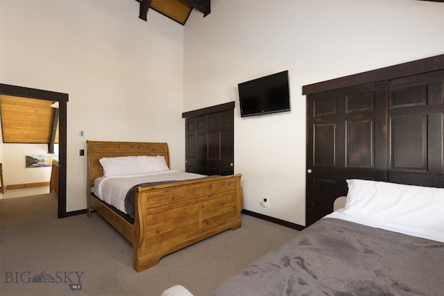 bedroom featuring a towering ceiling, light carpet, beam ceiling, and a closet