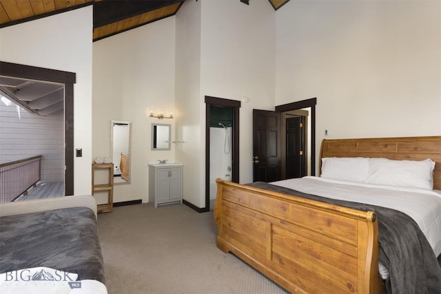 bedroom featuring high vaulted ceiling, light colored carpet, wooden ceiling, and ensuite bath