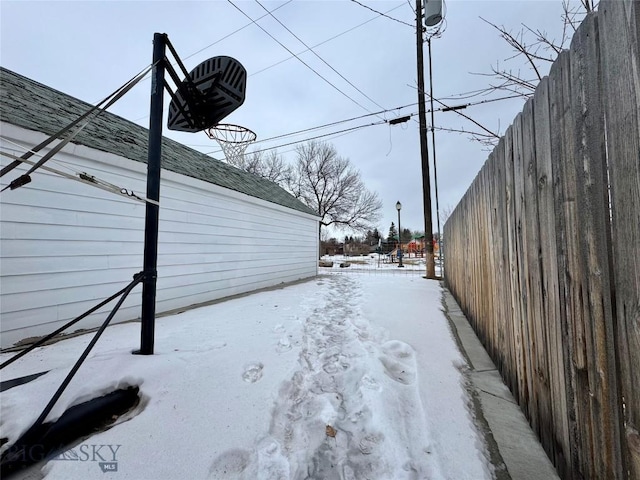 snowy yard featuring basketball court