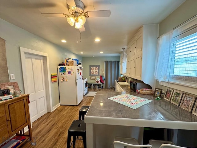 kitchen featuring sink, a kitchen breakfast bar, white refrigerator, kitchen peninsula, and light wood-type flooring