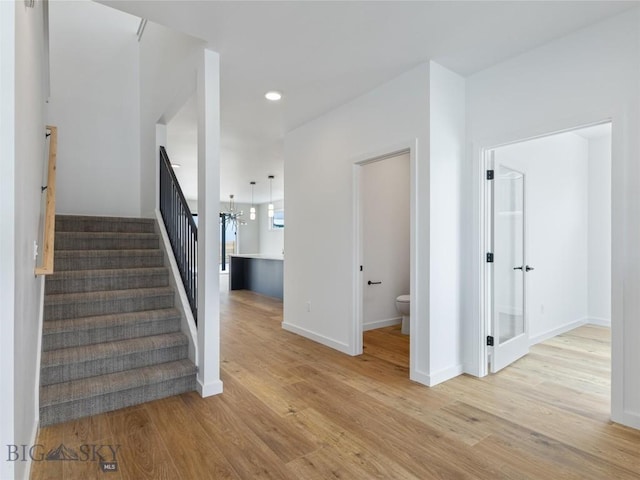 stairway with a notable chandelier and wood-type flooring