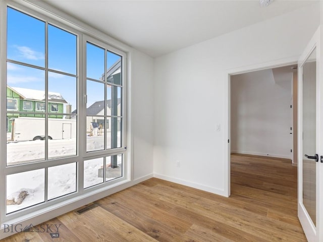 unfurnished room with french doors, a wealth of natural light, and light hardwood / wood-style flooring