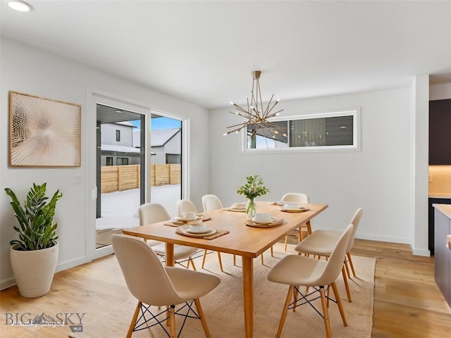 dining area with light hardwood / wood-style flooring and a chandelier