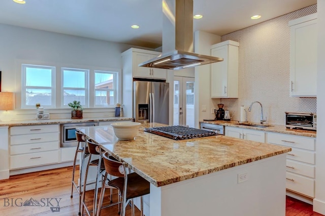 kitchen featuring white cabinetry, island range hood, stainless steel appliances, and a kitchen island