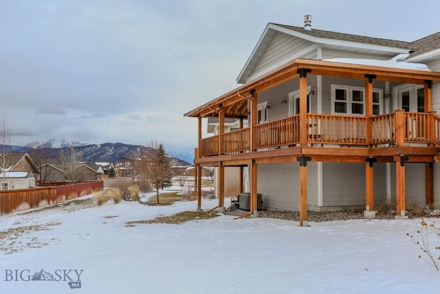 snow covered house with a mountain view and central AC unit