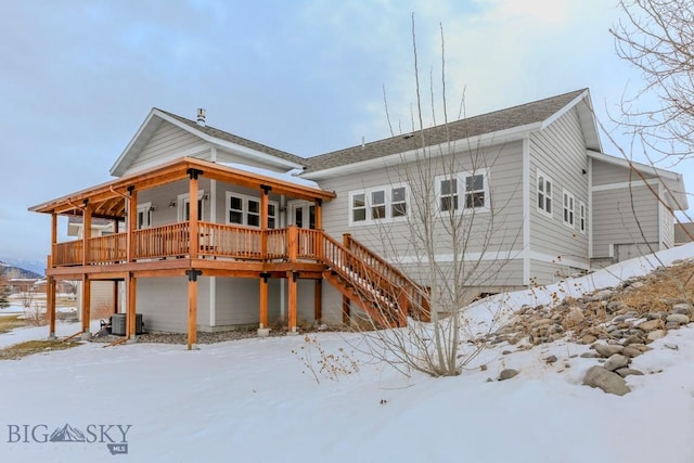 snow covered rear of property with central AC and a deck