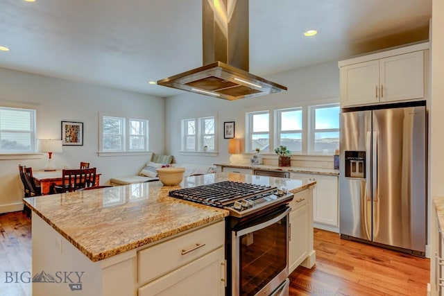 kitchen featuring white cabinetry, stainless steel appliances, a center island, and island exhaust hood