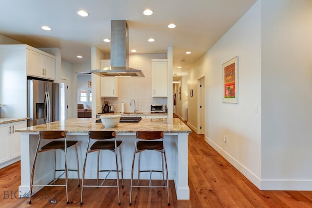 kitchen featuring island exhaust hood, a center island, stainless steel fridge with ice dispenser, and white cabinets