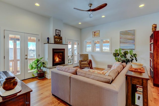 living room with french doors, ceiling fan, and light wood-type flooring