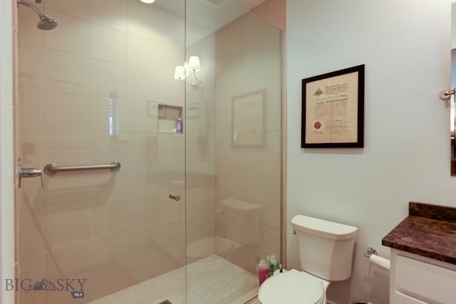 bathroom featuring vanity, toilet, and a tile shower