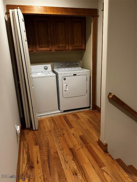 washroom featuring separate washer and dryer, cabinets, and light wood-type flooring