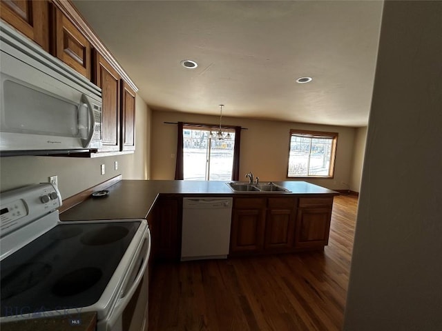 kitchen featuring sink, hanging light fixtures, dark hardwood / wood-style floors, kitchen peninsula, and white appliances