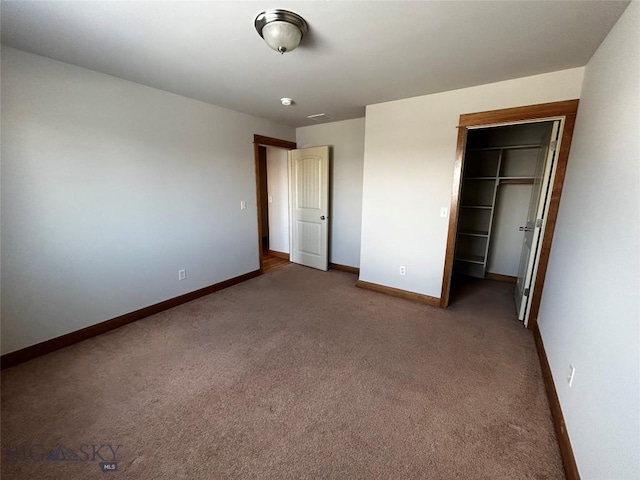 unfurnished bedroom with dark colored carpet, a spacious closet, and a closet