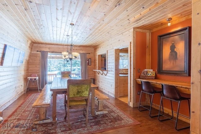 dining area featuring an inviting chandelier, wooden walls, wooden ceiling, and wood-type flooring