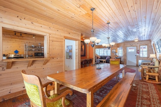 dining area with rail lighting, wood walls, a chandelier, wooden ceiling, and hardwood / wood-style floors