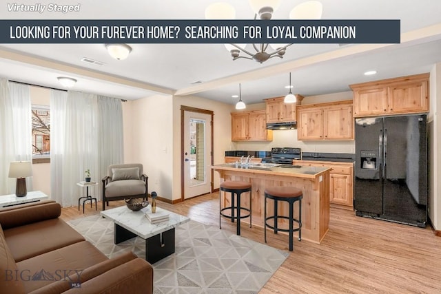 kitchen with light wood finished floors, range with electric cooktop, light brown cabinets, under cabinet range hood, and black fridge with ice dispenser