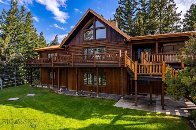 back of house with a wooden deck, a patio, and a lawn