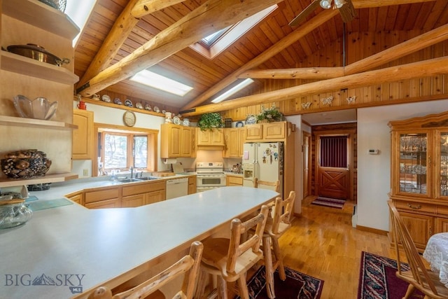 kitchen with a skylight, sink, light brown cabinets, white appliances, and light hardwood / wood-style flooring