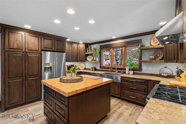 kitchen with sink, wooden counters, a center island, appliances with stainless steel finishes, and island exhaust hood