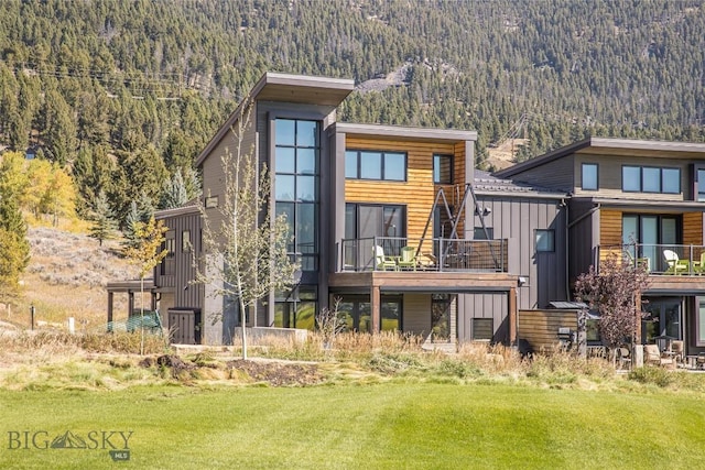 2174 Little Coyote Rd, Big Sky, MT 59716 - rear view of property with a view of trees, board and batten siding, a yard, and a balcony