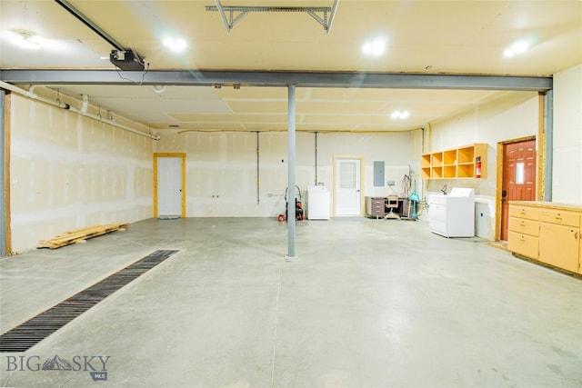 garage featuring electric panel, a garage door opener, and washing machine and clothes dryer