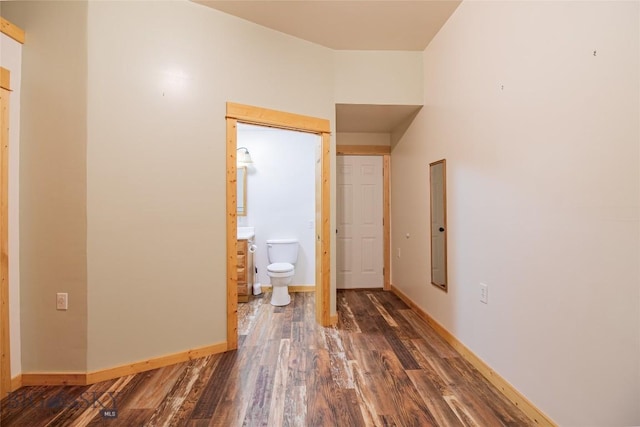 corridor featuring baseboards and wood finished floors