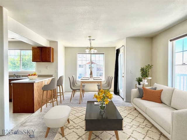 carpeted living room featuring sink, a textured ceiling, and a notable chandelier