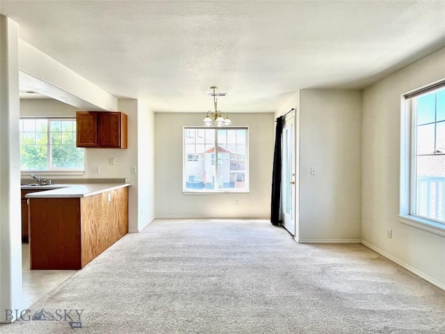 kitchen with decorative light fixtures, sink, a chandelier, light carpet, and a textured ceiling