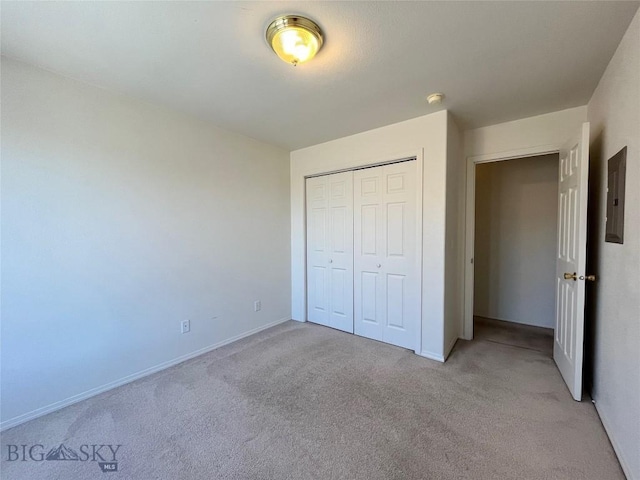 unfurnished bedroom featuring light colored carpet, electric panel, and a closet